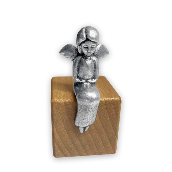 Silberner Metallengel sitzend auf Holzwürfel