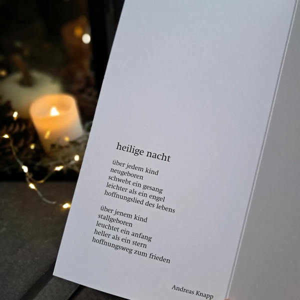 aufgeklappte weihnachtskarte, hintergrund kerze, lichterkette, tannenzapfen, stimmungsbild