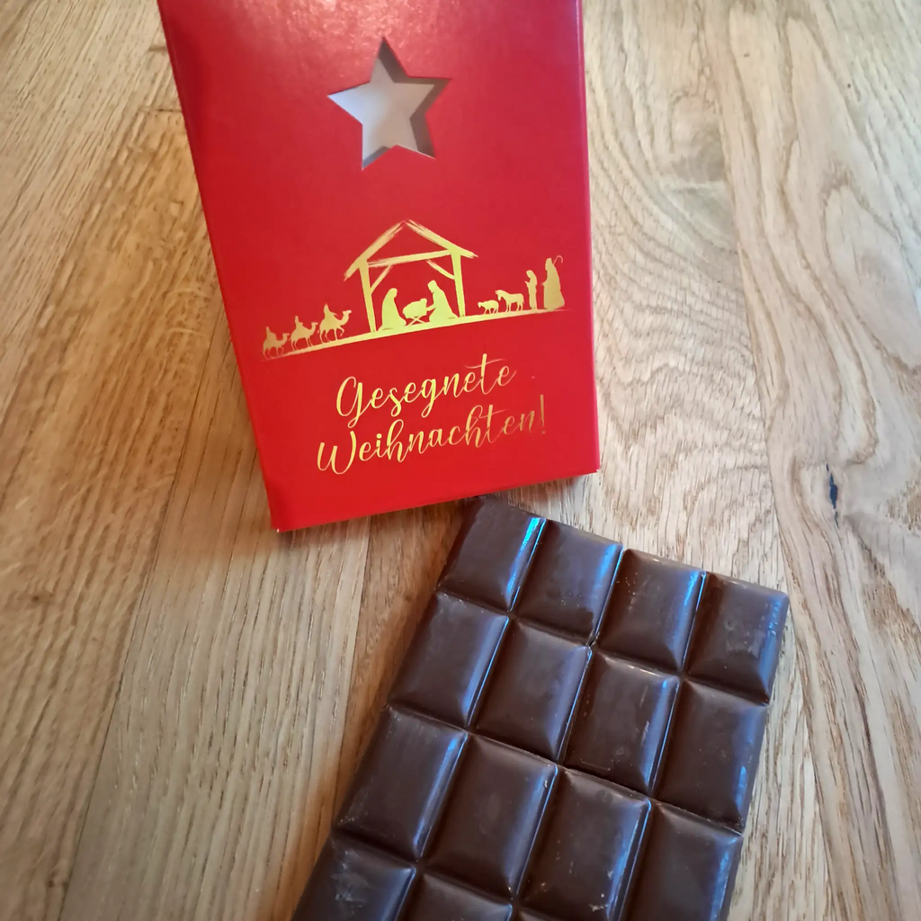 tafel schokolade, rote schachtel, sternausstanzung, krippe, maria, josef, jesuskind, ochse, esel, heilige 3 könige, aufschrift gesegnete weihnachten auf schachtel, tafel augespackt, stimmungsbild