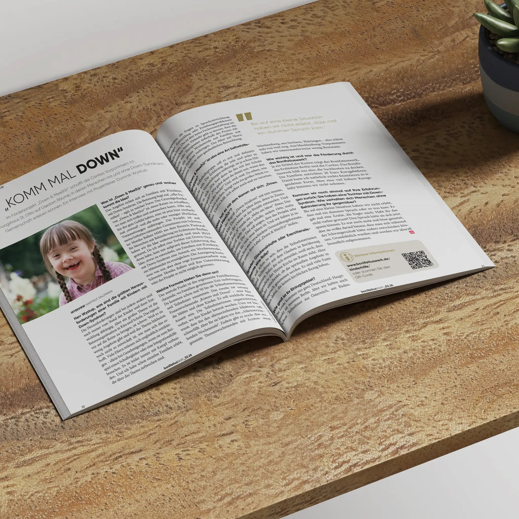 Innenansicht des bonifatiusblatt vom Bonifatiuswerk, aufgeschlagene Seite. Mädchen mit Downsyndrom auf Foto lachend, Artikel dazu mit der Headline "Komm mal Down".