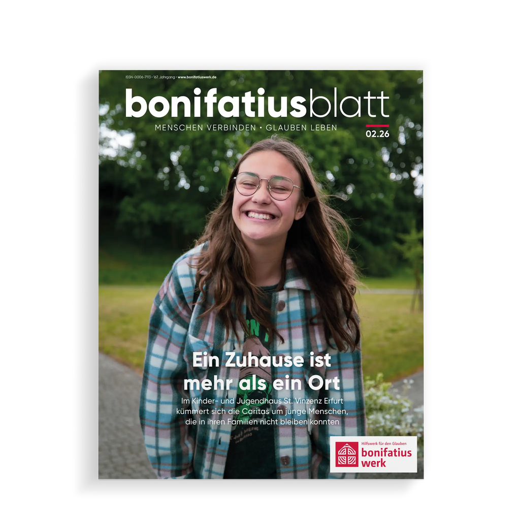 Titelblatt des bonifatiusblatt vom Bonifatiuswerk, junge Frau mit Brille steht im Garten und lacht.