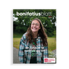 Titelblatt des bonifatiusblatt vom Bonifatiuswerk, junge Frau mit Brille steht im Garten und lacht.
