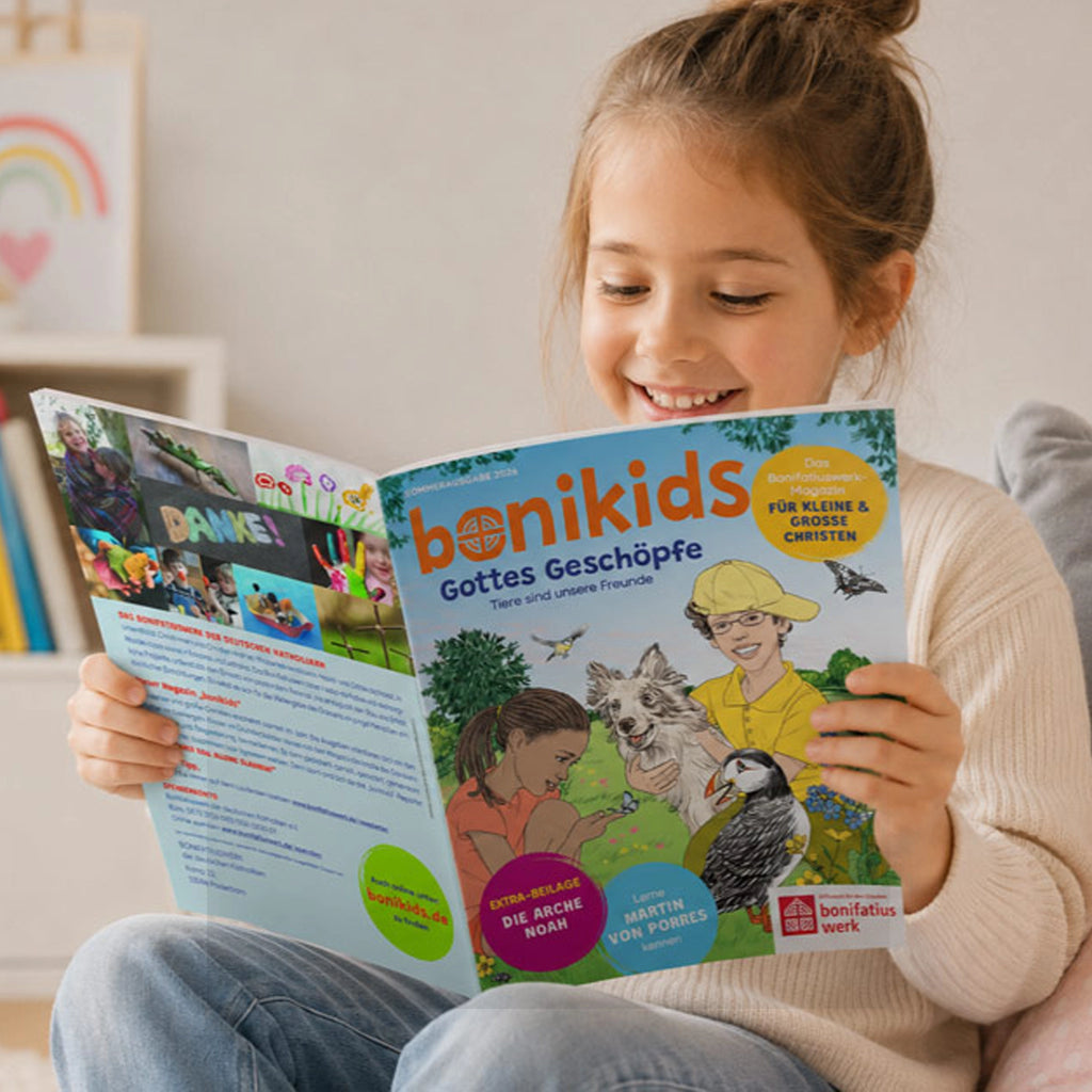 Mädchen hält bonikids-Kinderzeitschrift Sommerausgabe 2026. Der Titel zeigt Gottes Geschöpfe Tiere Papageientaucher, Hund, Vögel, Schmetterlinge, Bienen und einen Jungen und ein Mädchen auf einer Sommerwiese, in bunten Farben auf dem Cover.