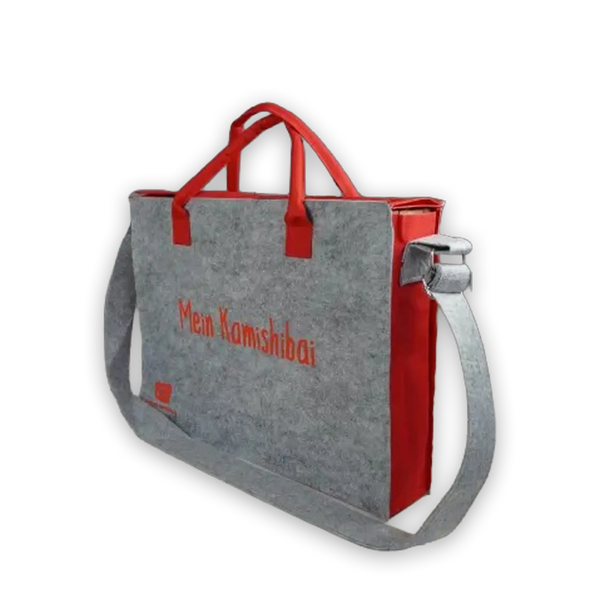 Graue Filztasche mit roten Griffen und Schultergurt, bedruckt mit „Mein Kamishibai“, Transporttasche für Kamishibai-Bildkarten.